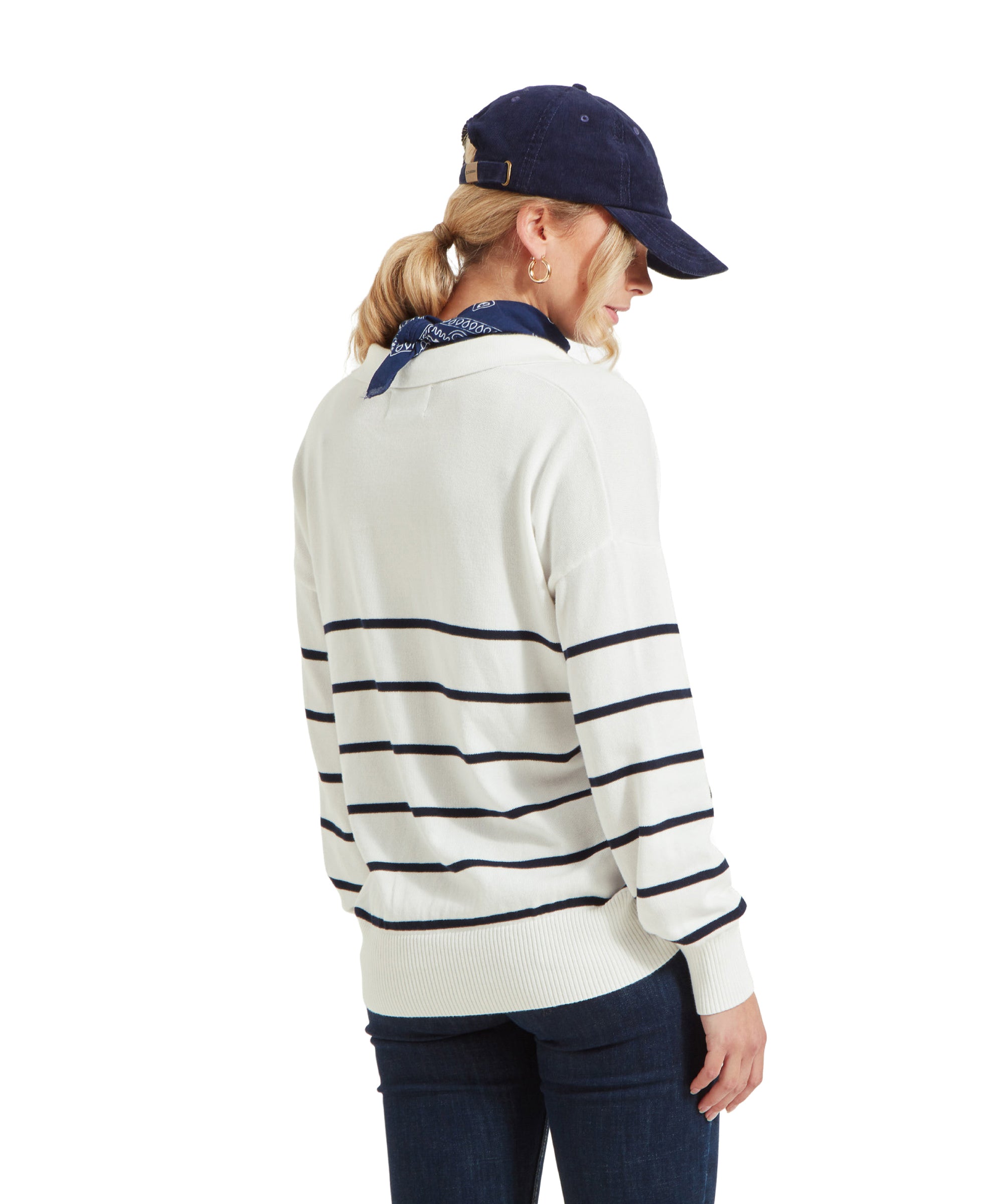 A woman wearing a Schöffel Roseland Jumper for Women in Navy, dark blue jeans, a navy blue cap, and a navy blue bandana around her neck, showing the back view of her outfit.