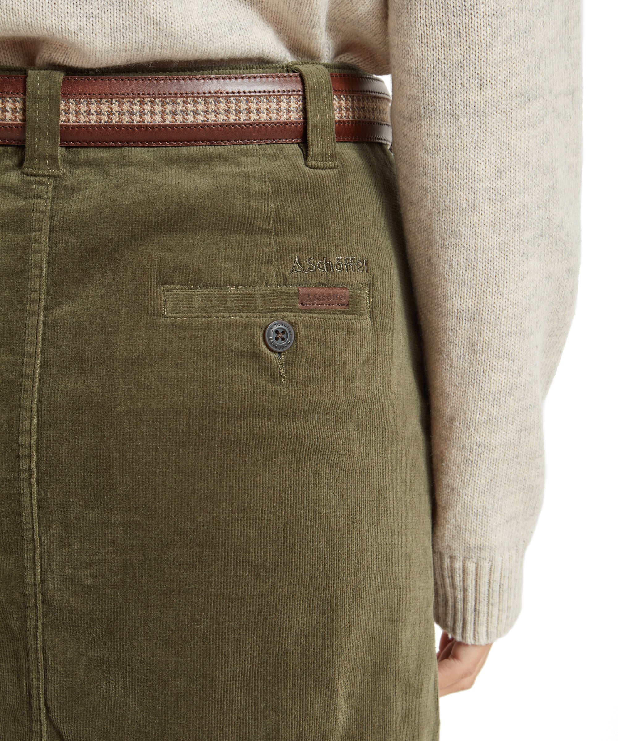 Close-up of the back of the Schöffel Sage Cord Skirt for Women in Green. The image highlights the back pocket details, stitching, and the embroidered Schoffel logo on the pocket, along with the brown belt.