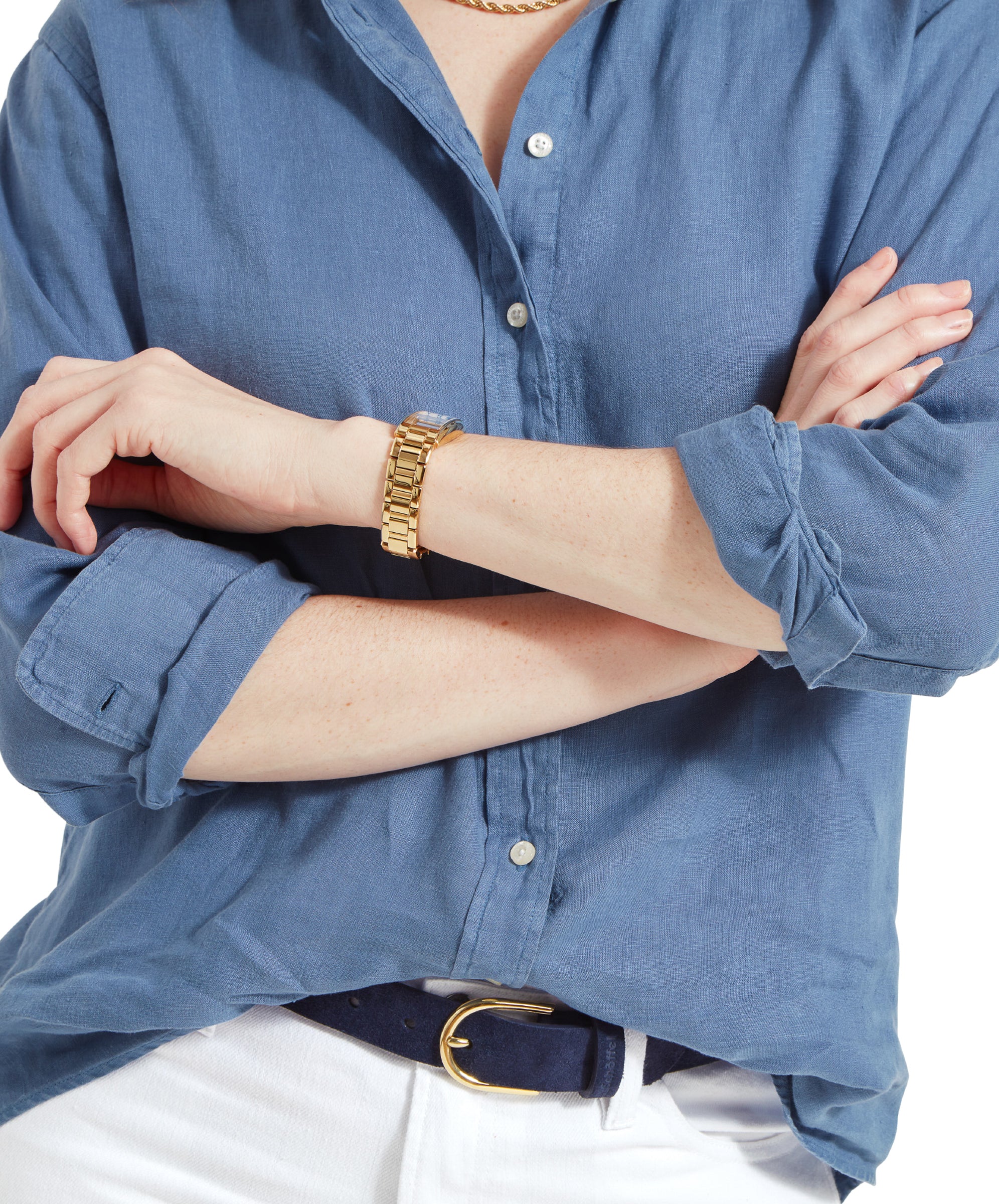 Close-up of the woman's arms crossed, highlighting the Schöffel Salthouse Linen Shirt for Women in Blue and gold wristwatch, and a blue belt.