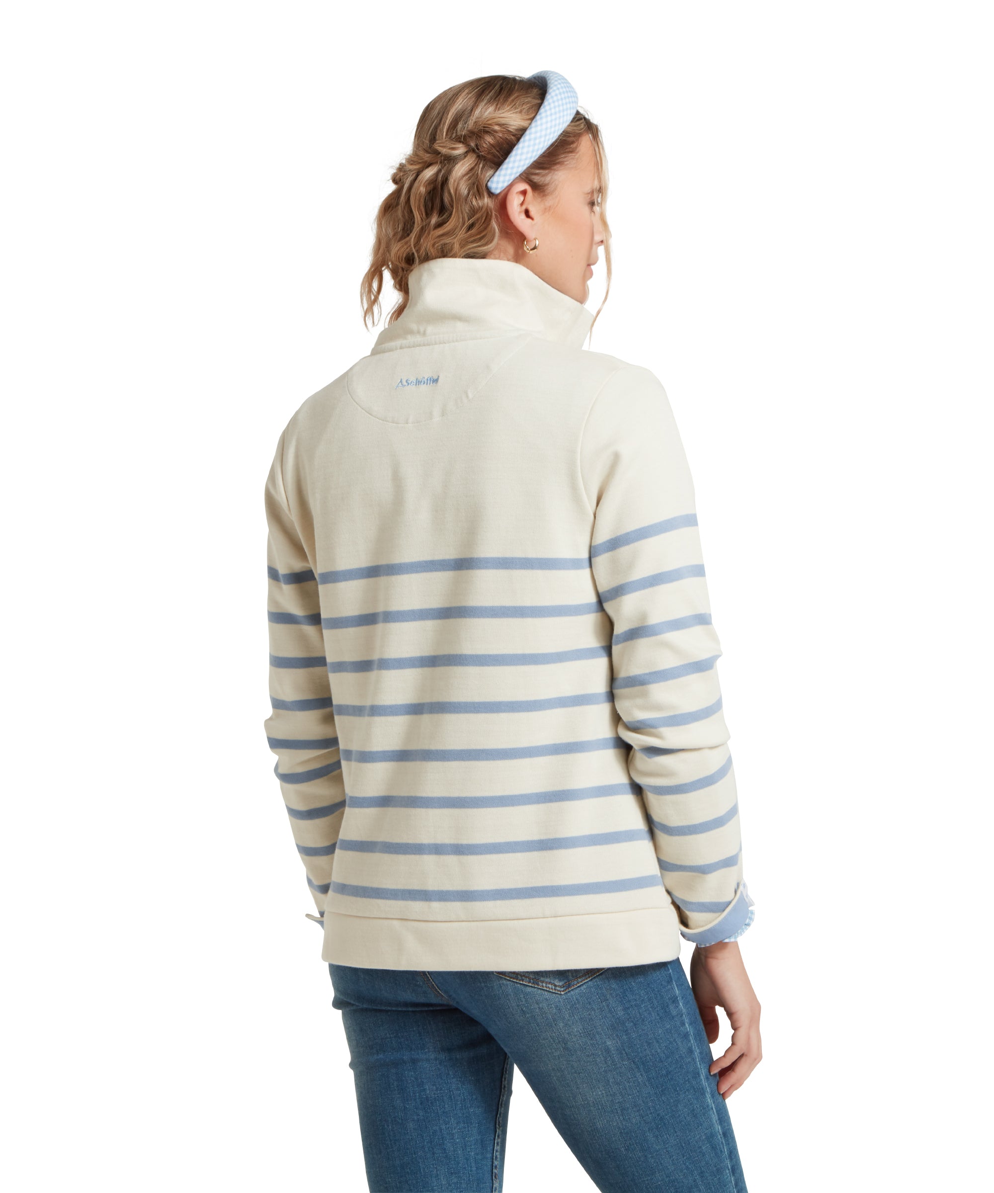 Rear view of a female model wearing a blue and beige striped Schöffel sweatshirt with a small 'Schöffel' logo on the back, paired with denim blue jeans.