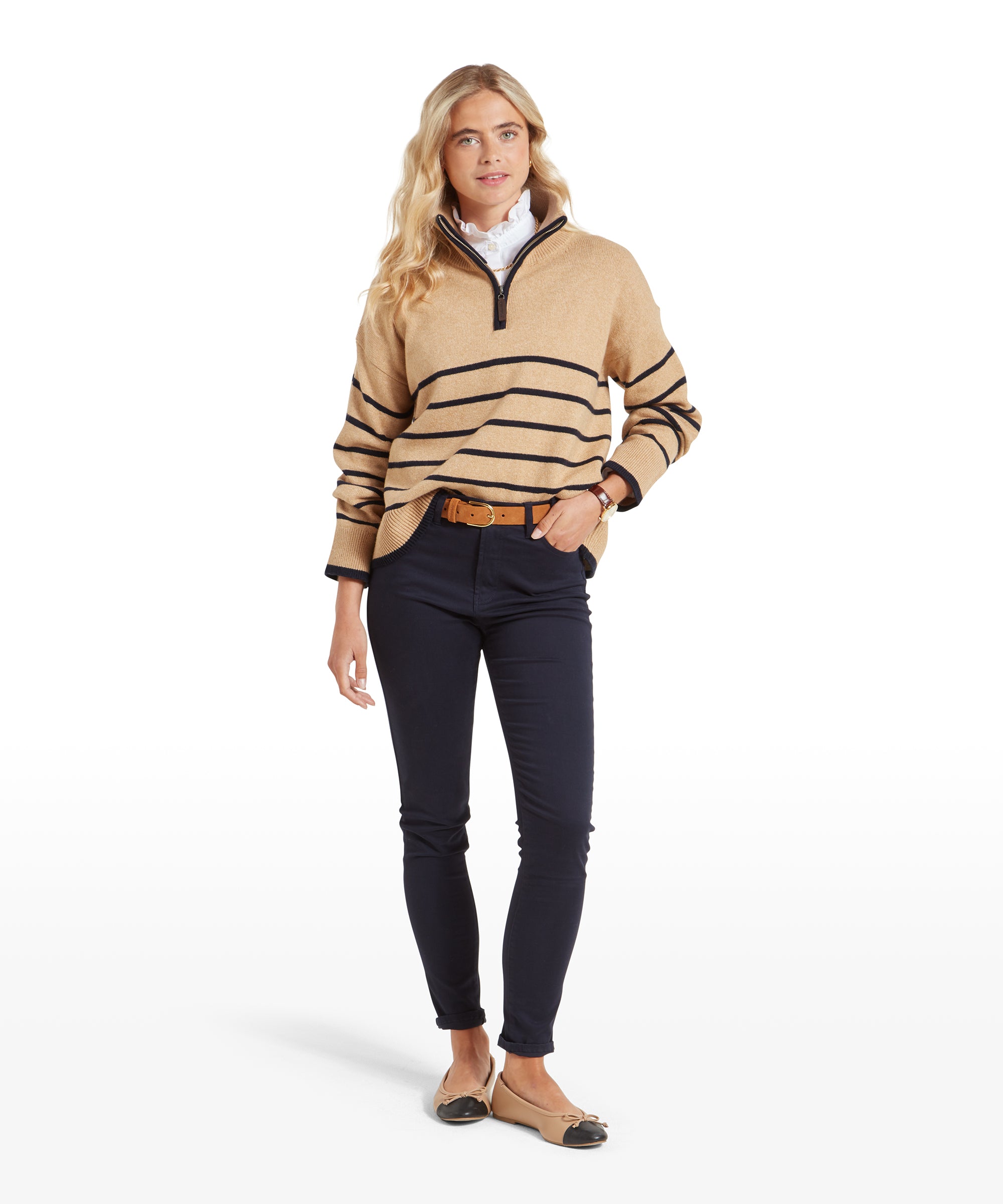 Full-body view of the woman wearing the Schöffel Sandsend 1/4 Jumper for Women in Beige with navy trousers and tan belt. She stands with one hand in her pocket, exuding a relaxed, stylish vibe.