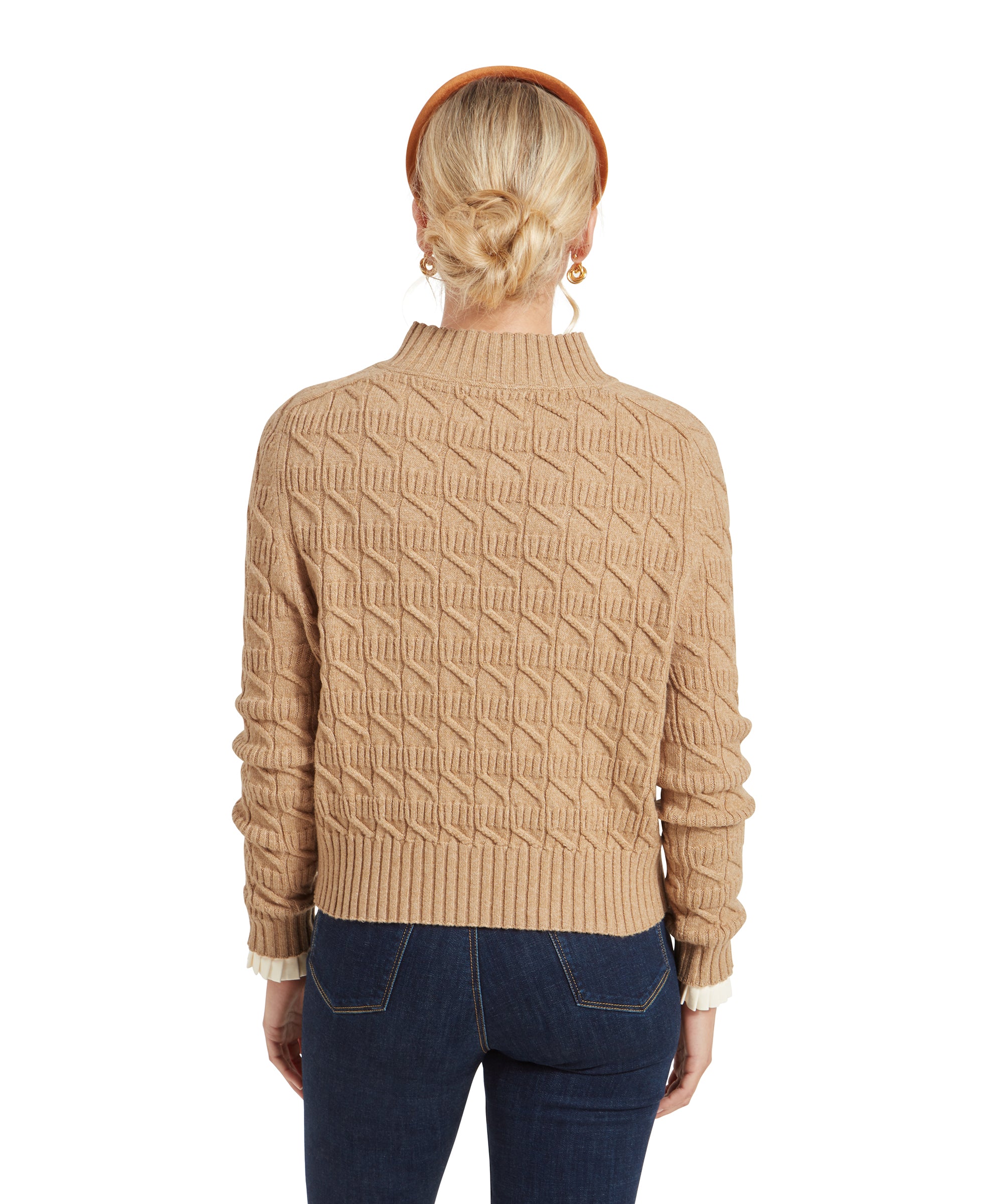 A rear view of the same woman wearing the Schöffel Sandsend Cable Jumper for Women in Beige, highlighting the design and fit of the jumper with the geometric pattern.