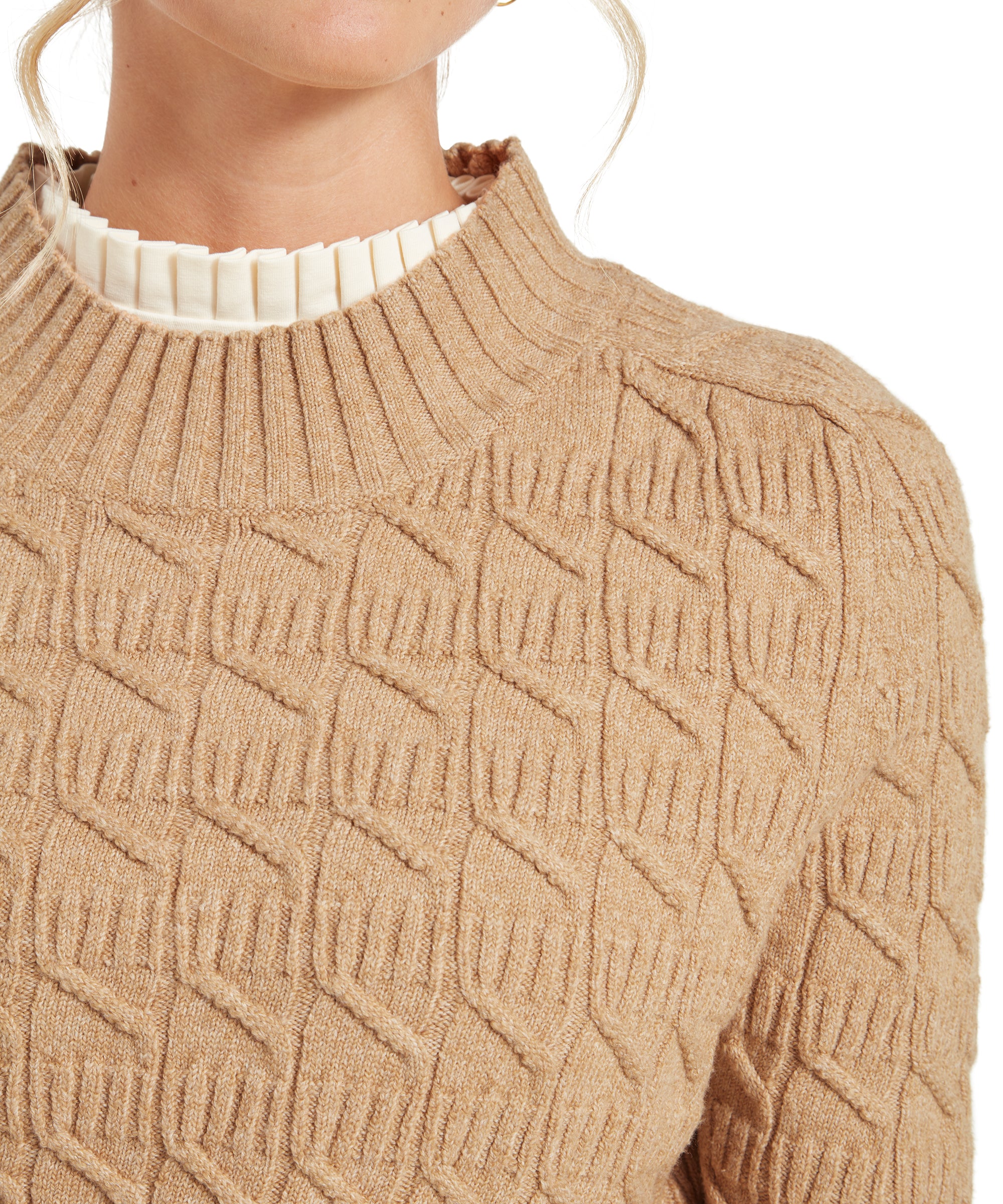 Close-up of the Schöffel Sandsend Cable Jumper for Women in Beige showcasing its geometric pattern and ribbed collar. The top of a cream blouse with a pleated collar is visible underneath.