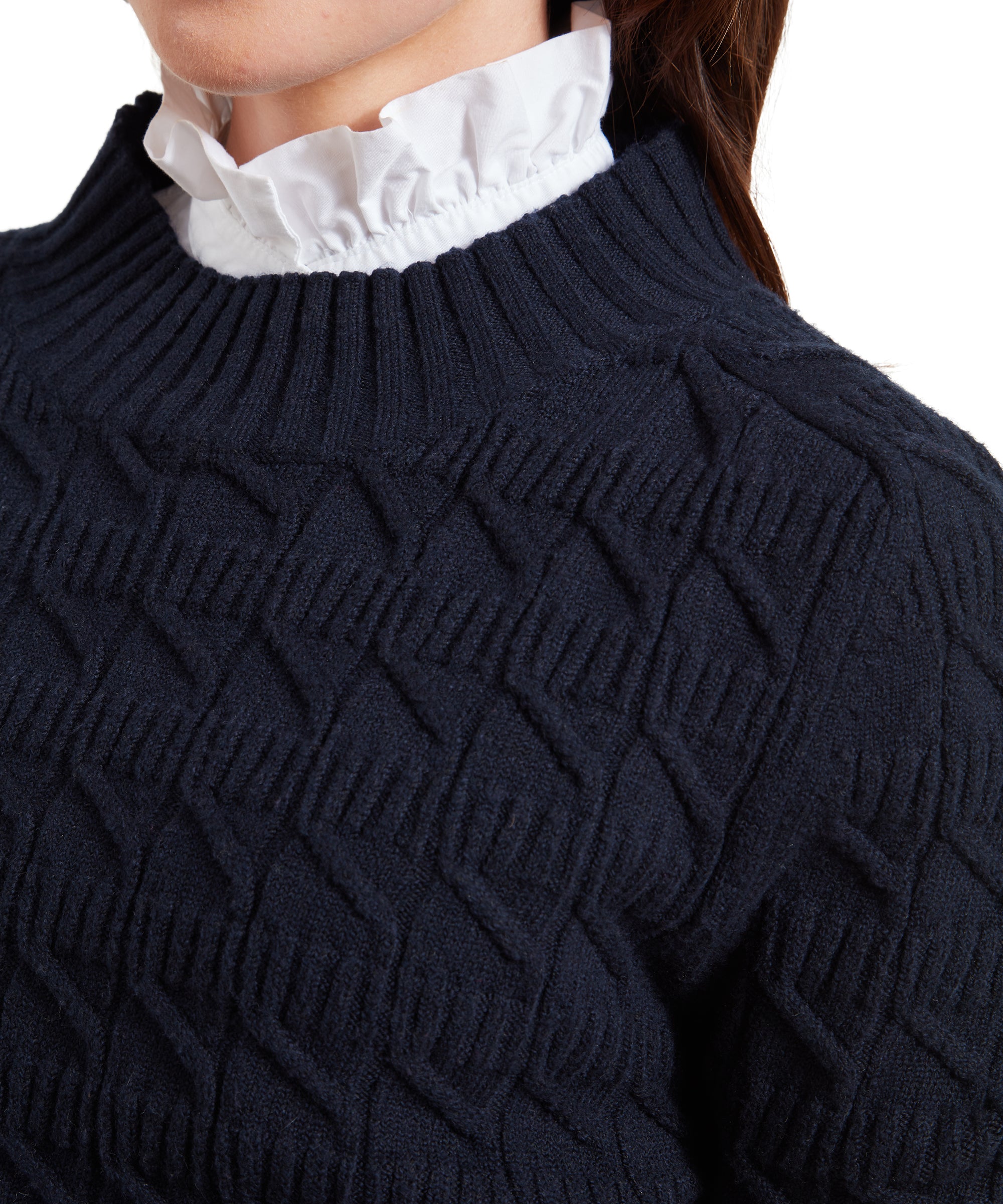 A close-up shot focusing on the textured collar of the Schöffel Sandsend Cable Jumper for Women in Navy. The woman is wearing a white ruffled shirt underneath, with the ruffle peeking out at the collar.