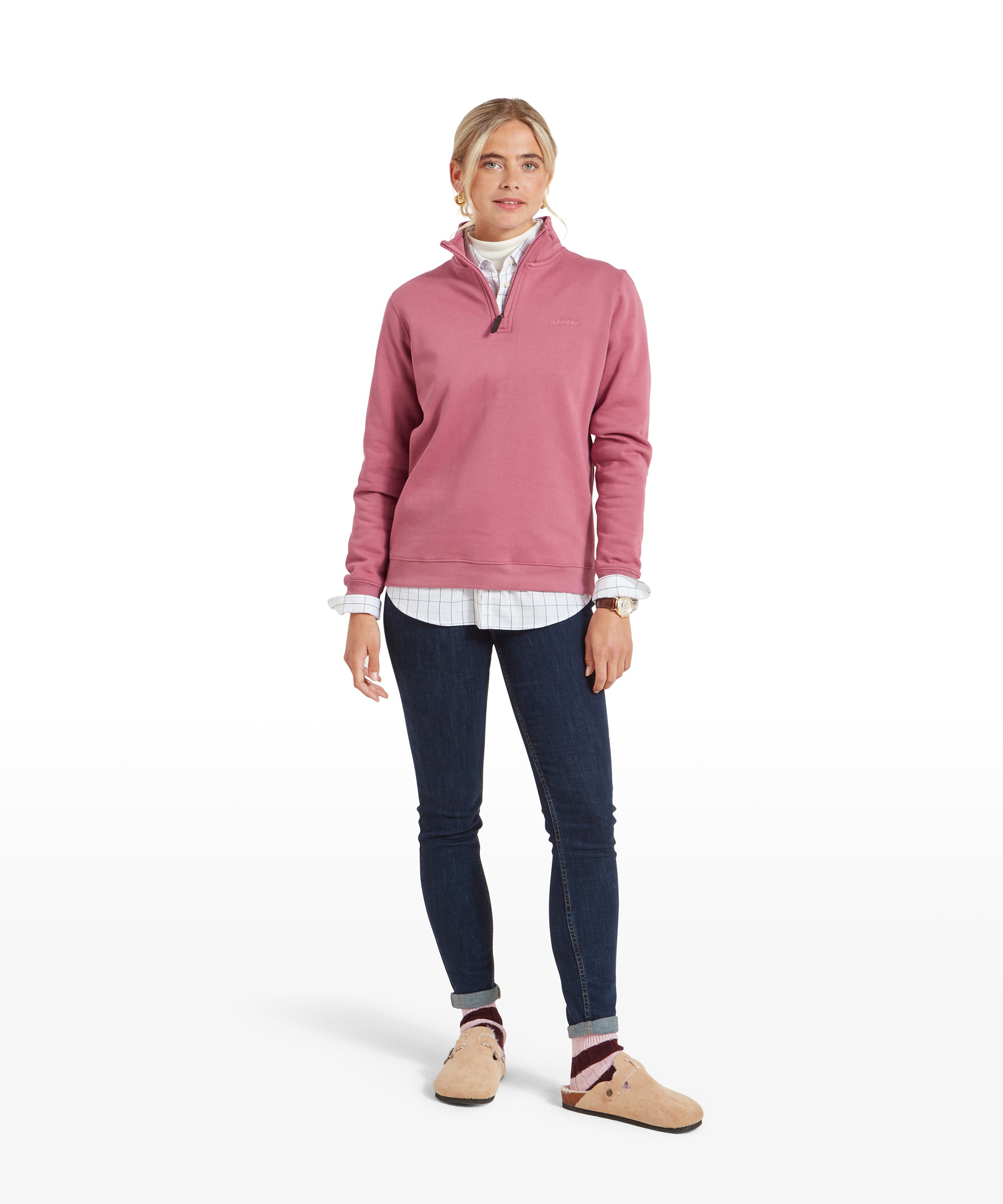 A full-body shot of the woman in the Schöffel Sennen Cove Sweatshirt for Womens in Pink, paired with dark skinny jeans and slip-on shoes, posing casually.