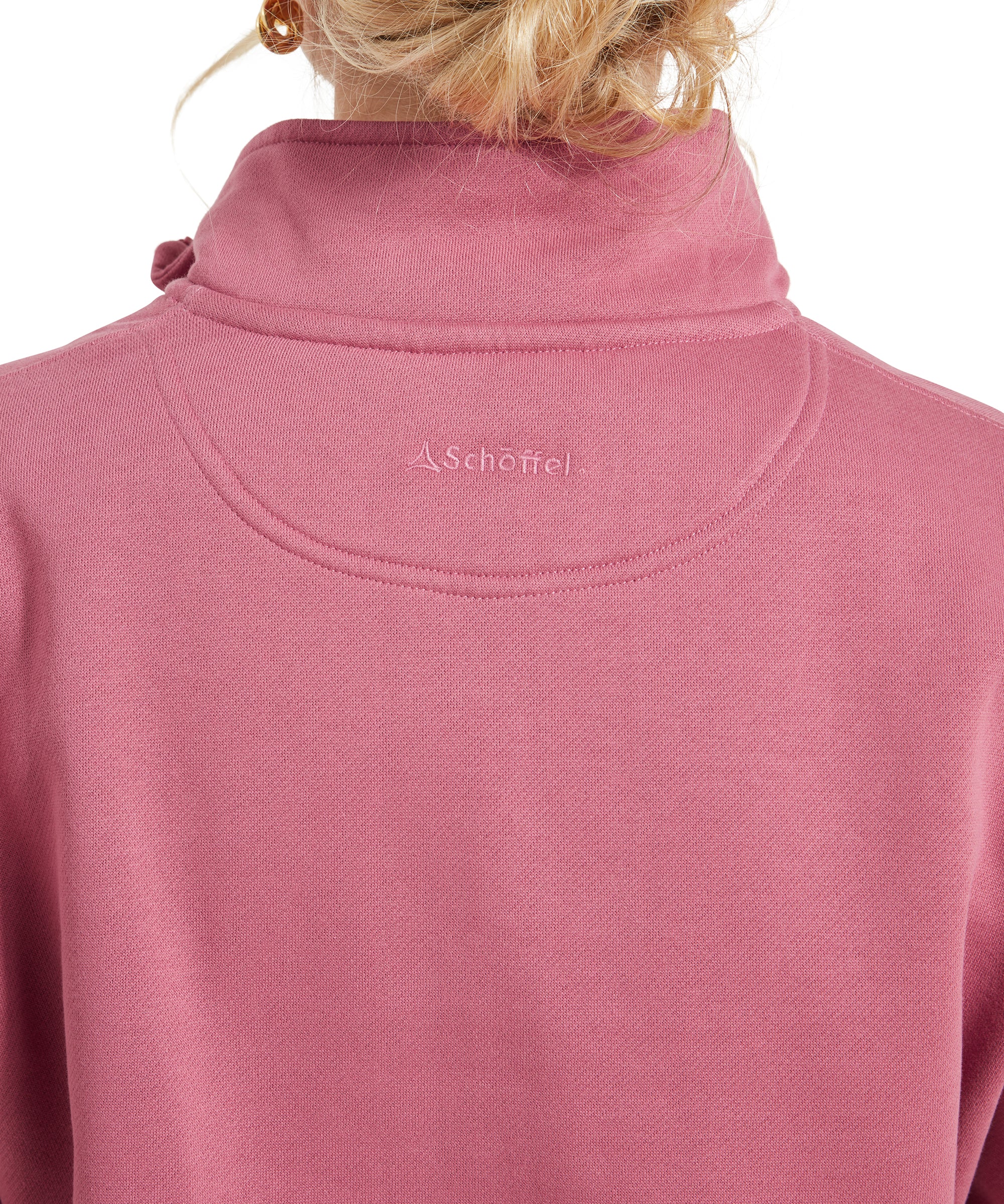 Close-up of the embroidered logo and stitching detail on the back of the Schöffel Sennen Cove Sweatshirt for Womens in Pink, with the woman's hair tied up.