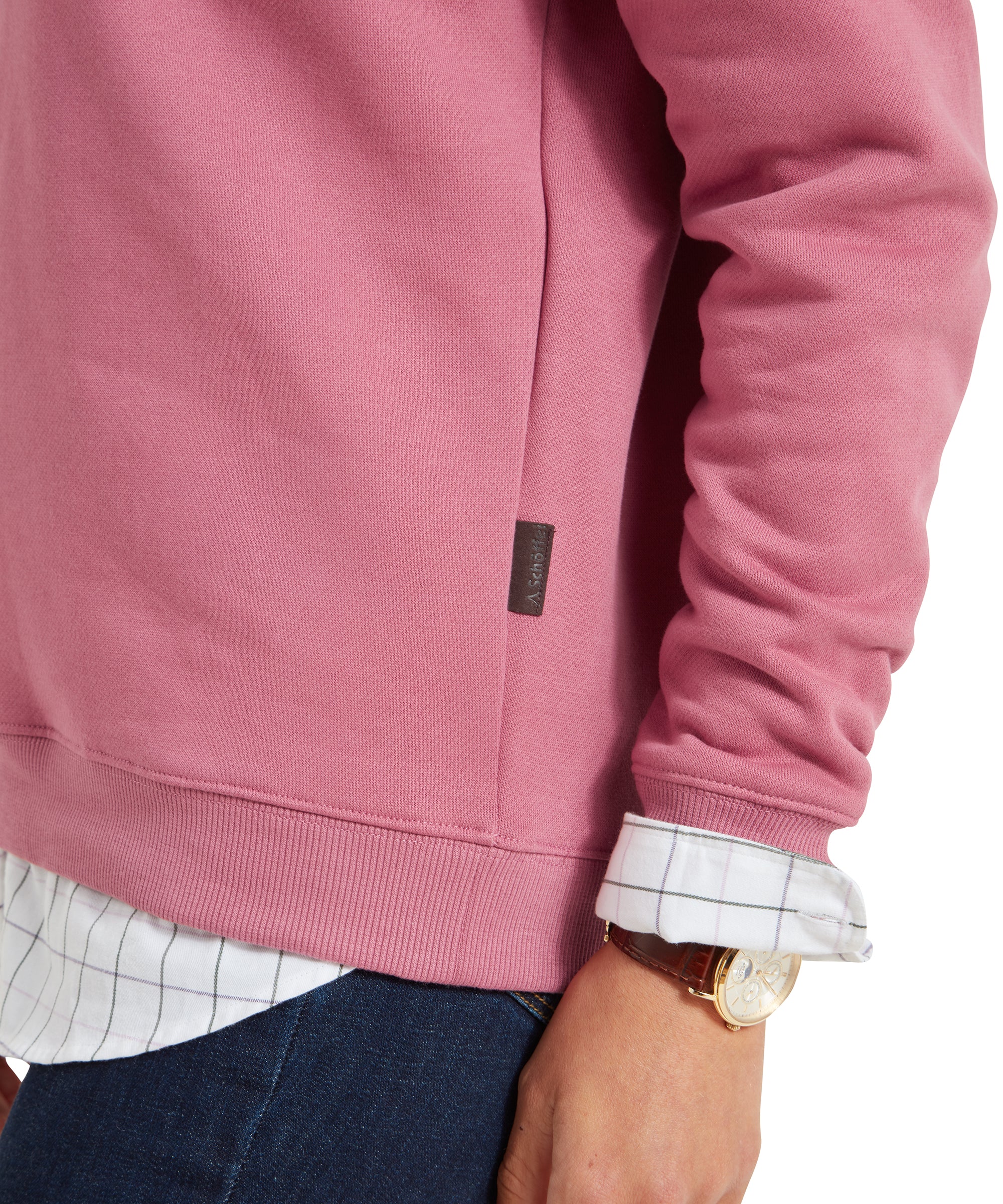 A close-up shot of the side seam and hem of the Schöffel Sennen Cove Sweatshirt for Womens in Pink, showing the label and the layered shirt underneath.