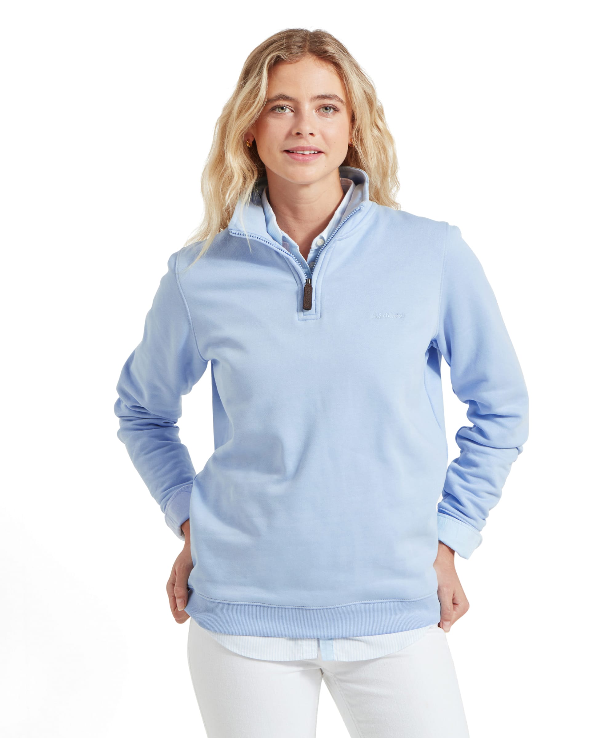 Front view of the woman wearing the Schöffel Sennen Cove Sweatshirt for Womens in Blue with her hands in the front pockets, smiling at the camera.