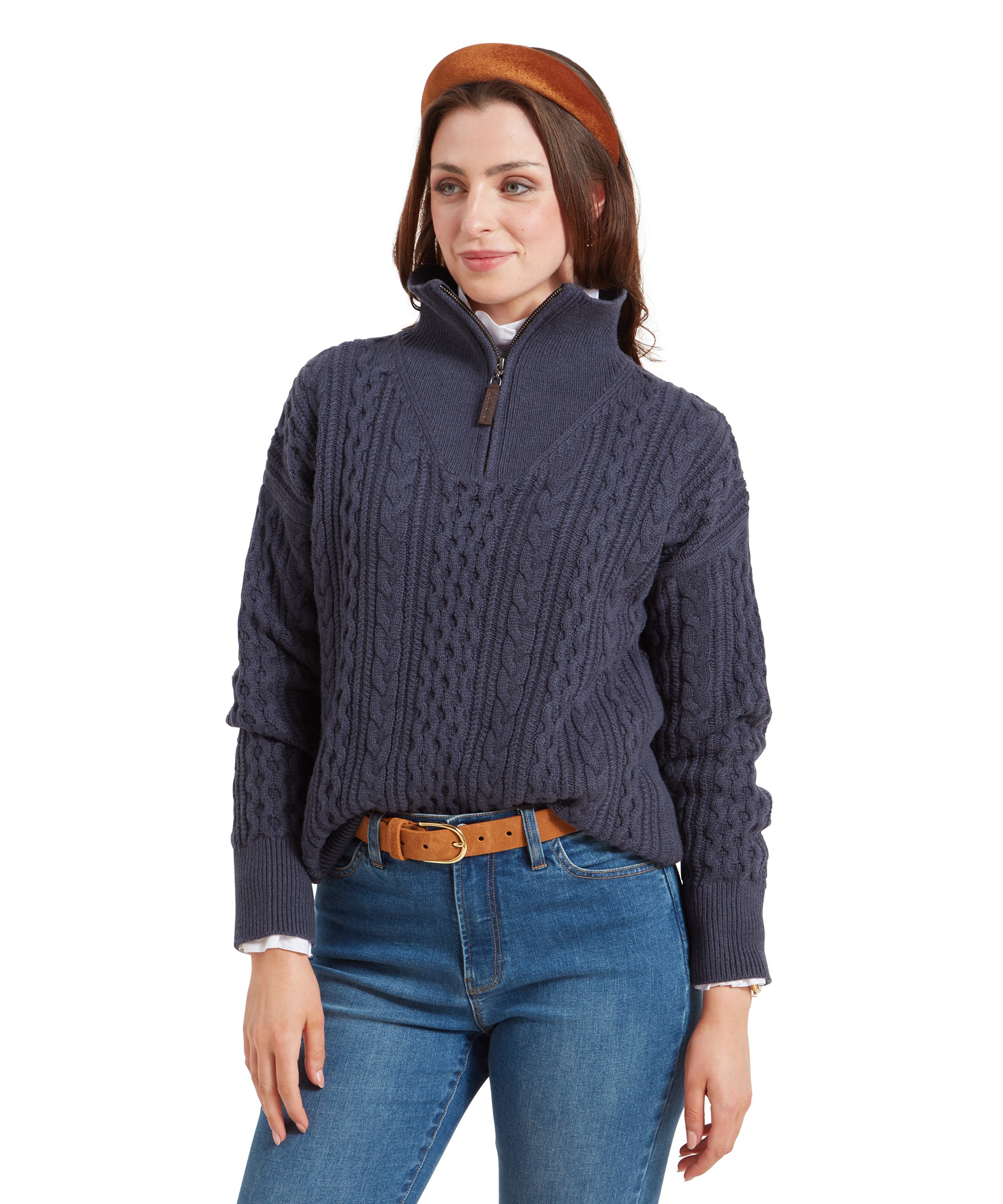 A woman wearing a Schöffel Settle 1/4 Zip for Women in Navy with a quarter-zip collar. The sweater is paired with blue jeans and a brown belt. She is smiling softly and wearing a brown headband, with her hands relaxed at her sides.