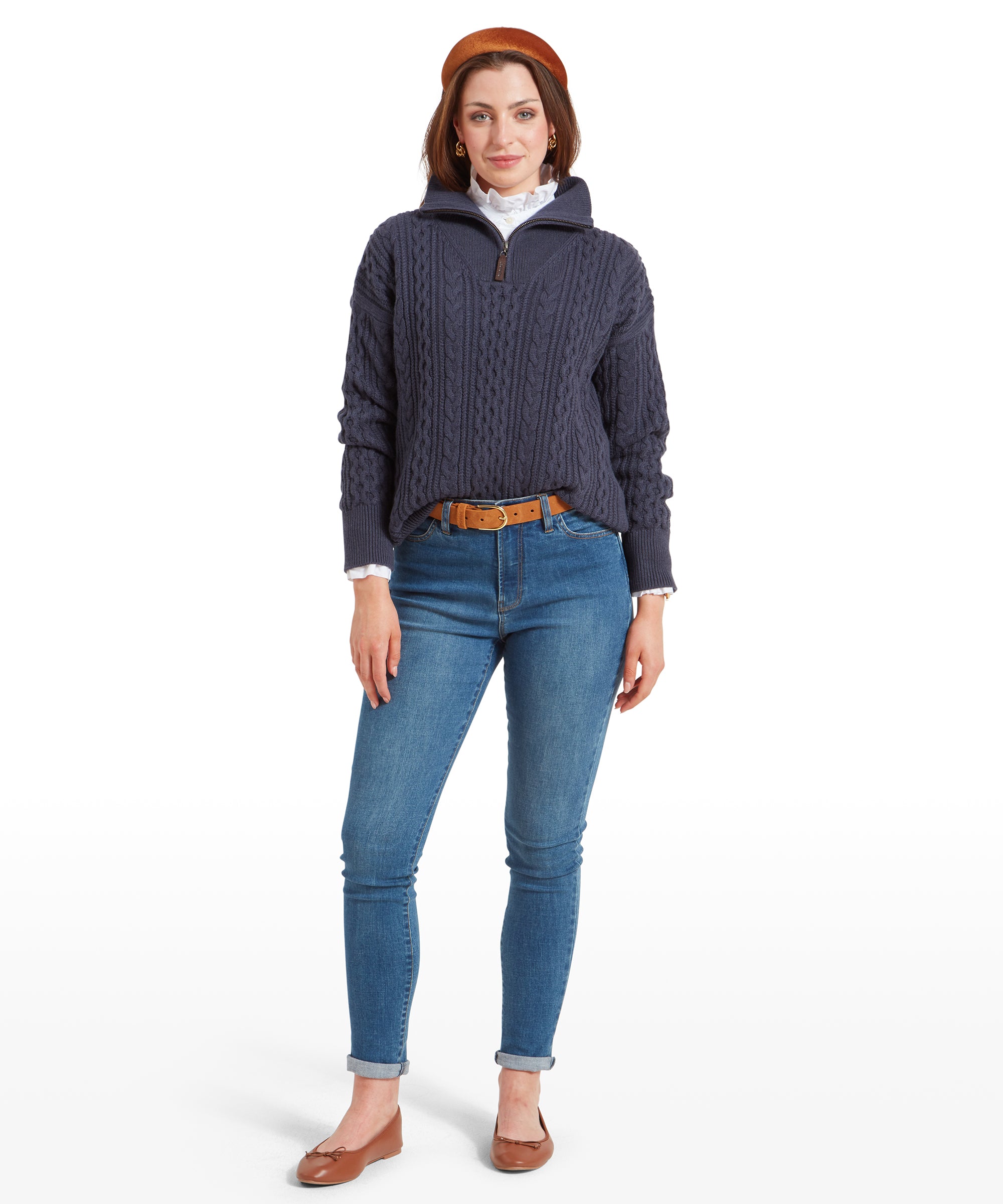 A full-body shot of the woman wearing the Schöffel Settle 1/4 Zip for Women in Navy and blue jeans. She stands with one foot slightly forward, hands by her sides, and is smiling slightly, showing the outfit in a casual and relaxed pose.