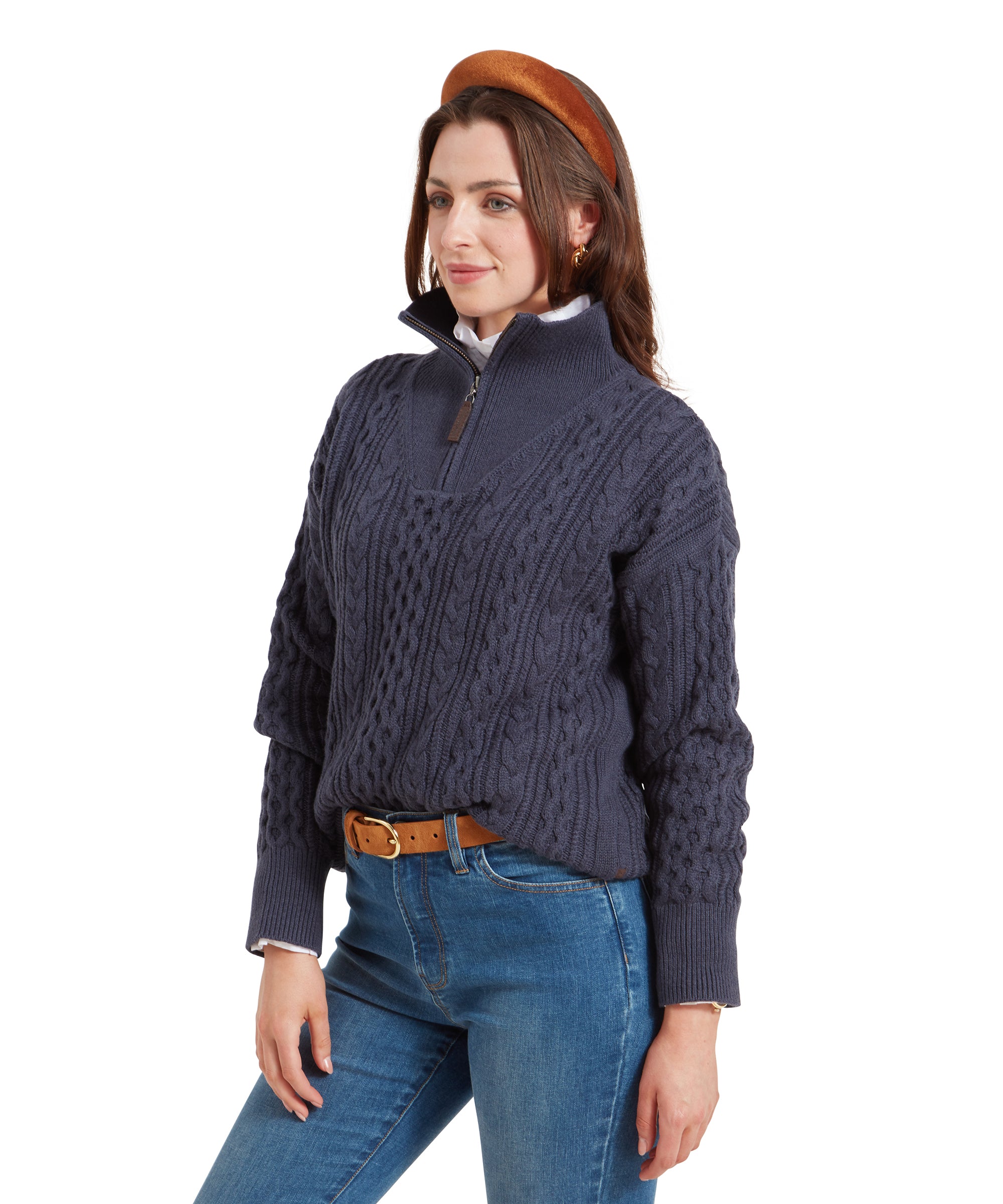 A side profile of the woman wearing the Schöffel Settle 1/4 Zip for Women in Navy, showcasing the quarter-zip collar and textured knit pattern. She is standing slightly angled with her hands gently crossed in front.