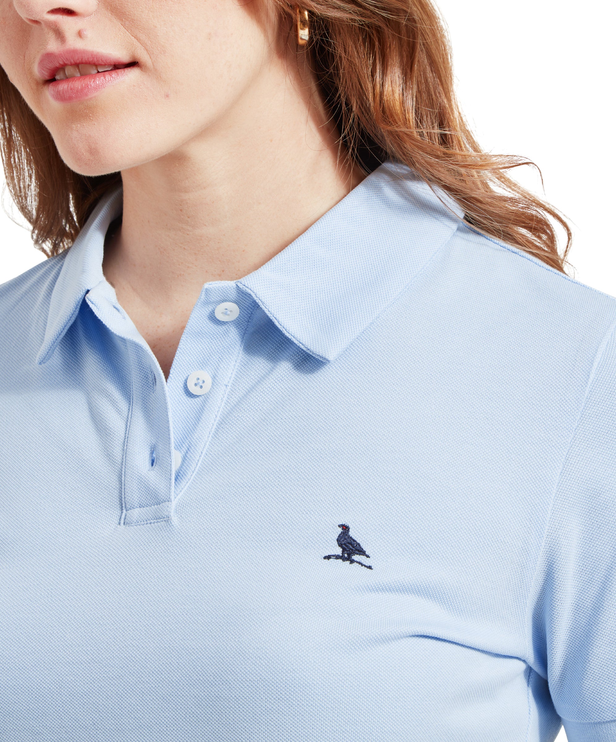 A close-up view of the dress's collar area, focusing on the small embroidered bird logo on the left chest. The fabric of the Schöffel St Ives Polo Dress for Women in Blue looks textured and soft, and the collar is neatly folded, adding a classic touch to the casual dress.