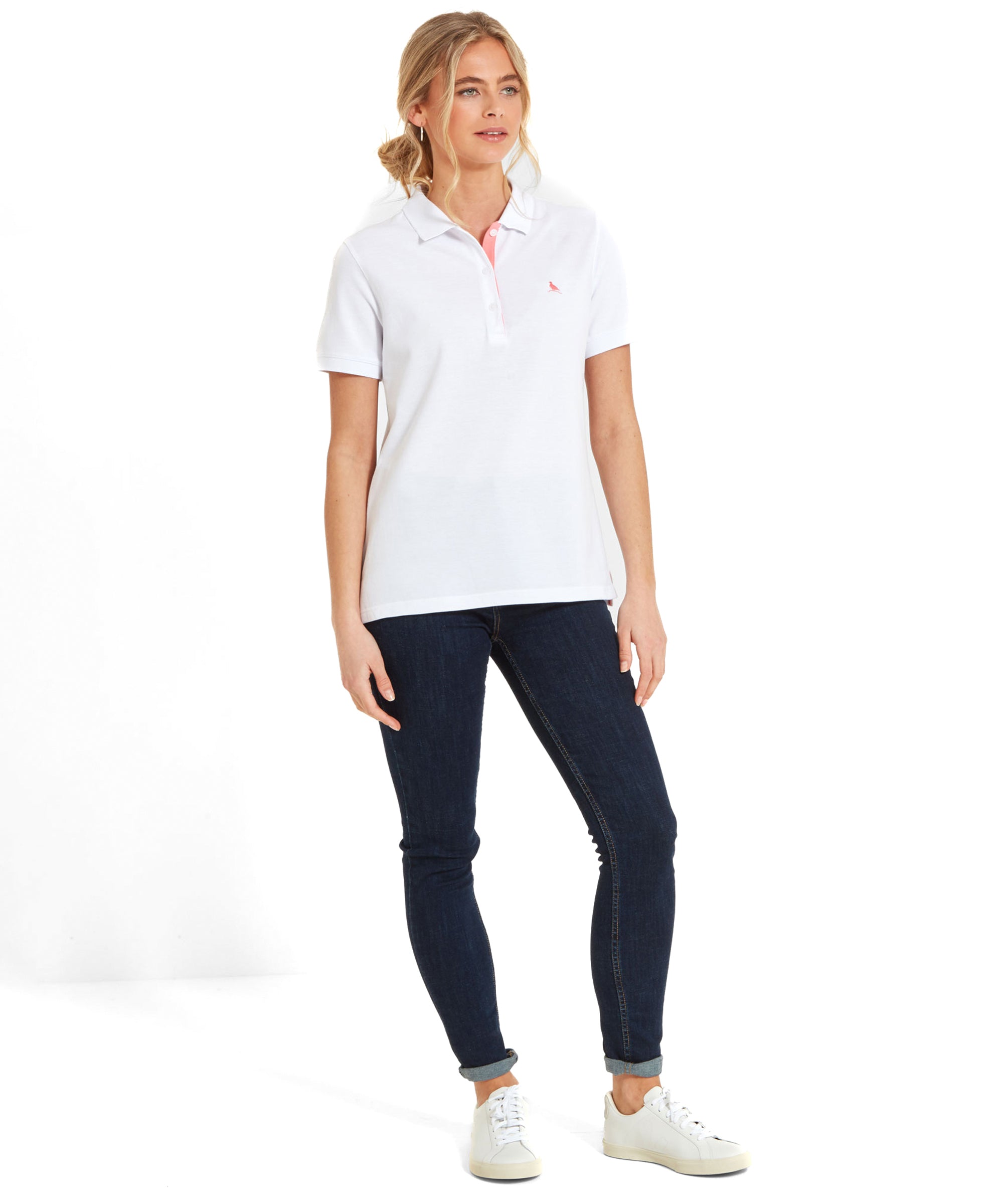 Full view of the woman in a Schöffel Women's St Ives Polo Shirt for Women in White and blue jeans and white trainers. Her hands hanging to the sides.