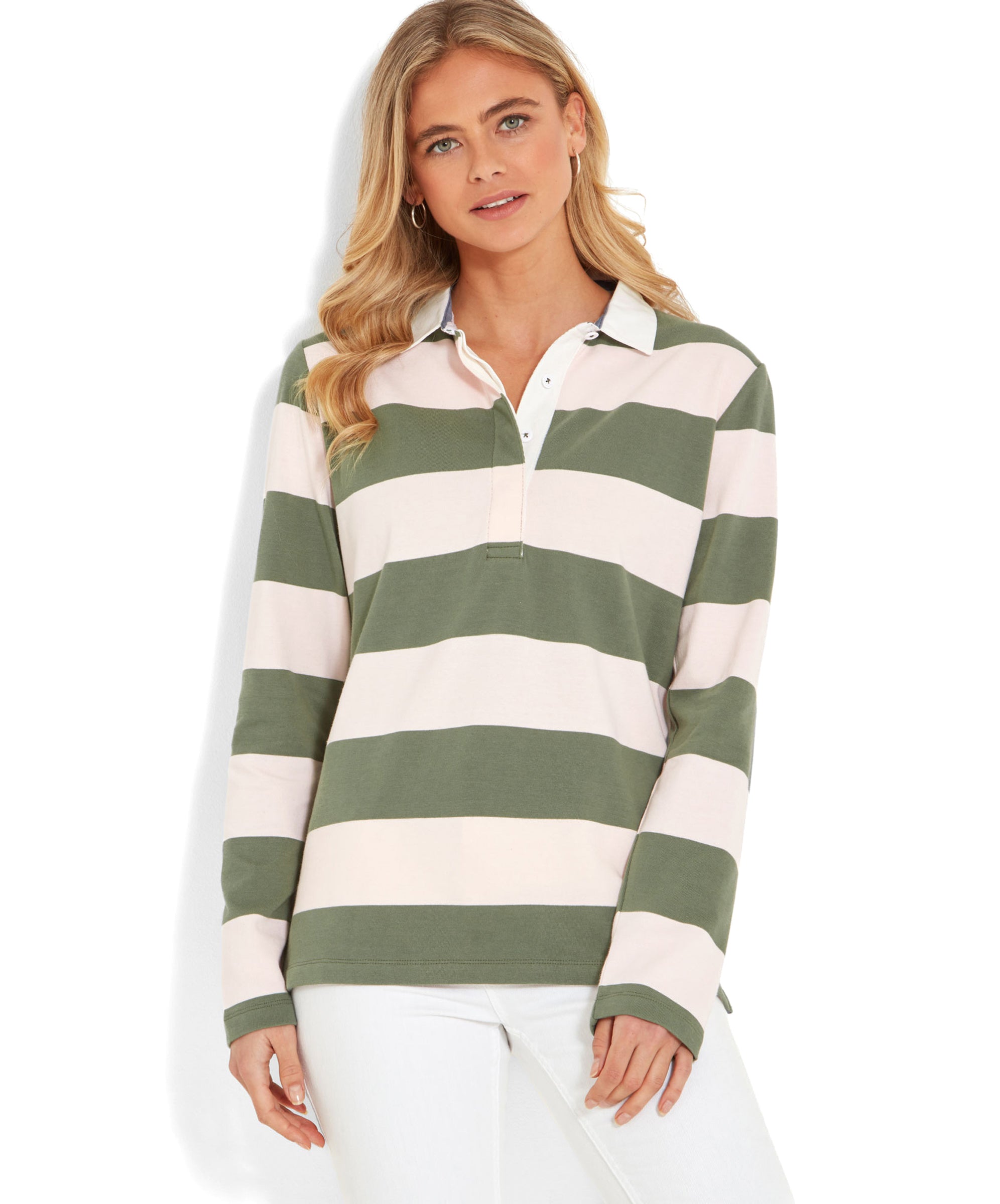 A woman wearing the Schöffel St Mawgan Rugby Shirt for Women in Pink and olive green stripes. She is posing with a slight smile, and her blonde hair is styled in loose waves. The shirt has broad horizontal stripes and a white collar, paired with white trousers.