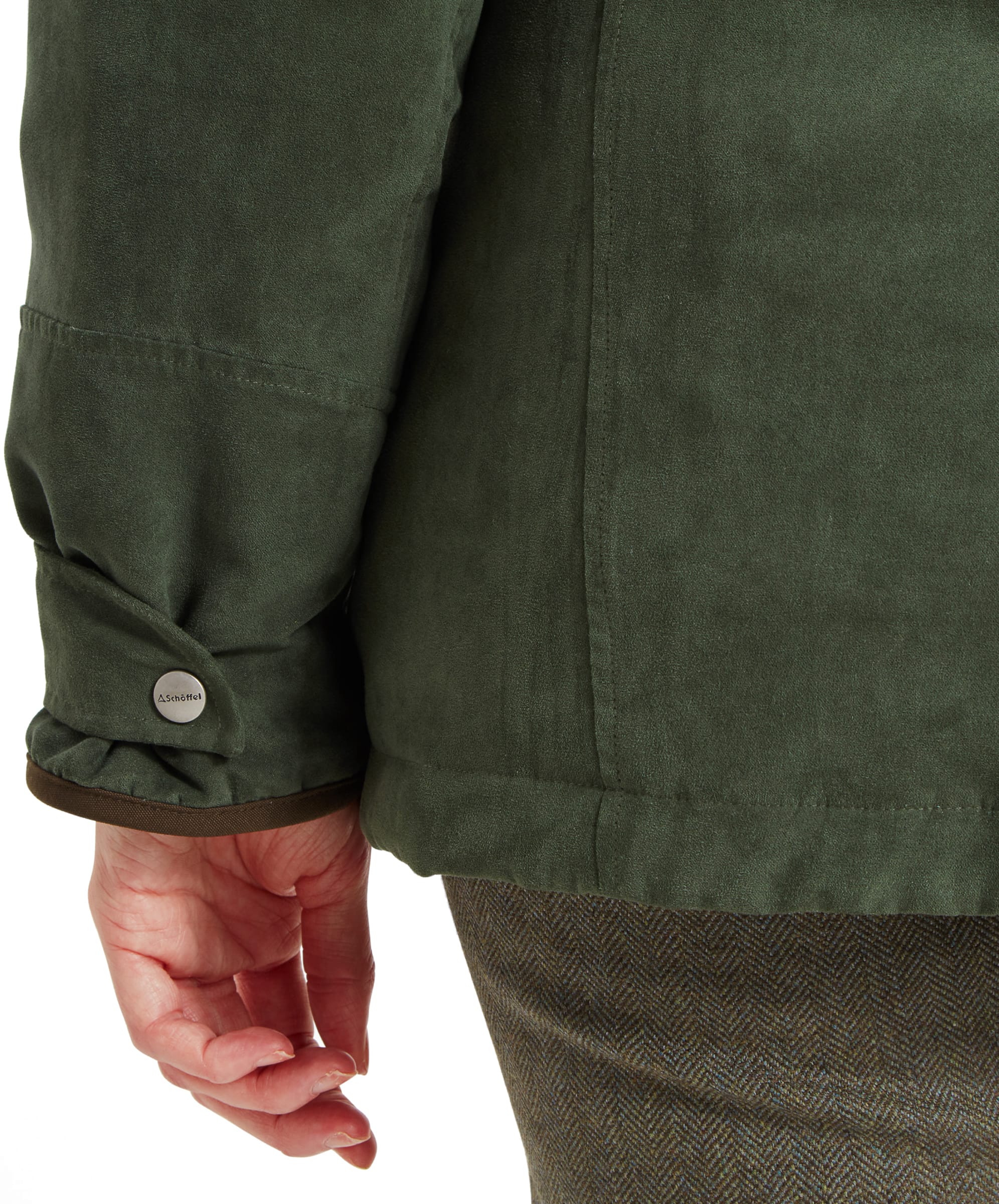 A close-up view of the Schöffel Teal Shooting Coat for Women in Green’s sleeve and cuff, showing the suede-like texture of the fabric. The cuff is secured with a snap button that bears the brand's name, “Schöffel.” The hand is relaxed, hanging naturally by the side.