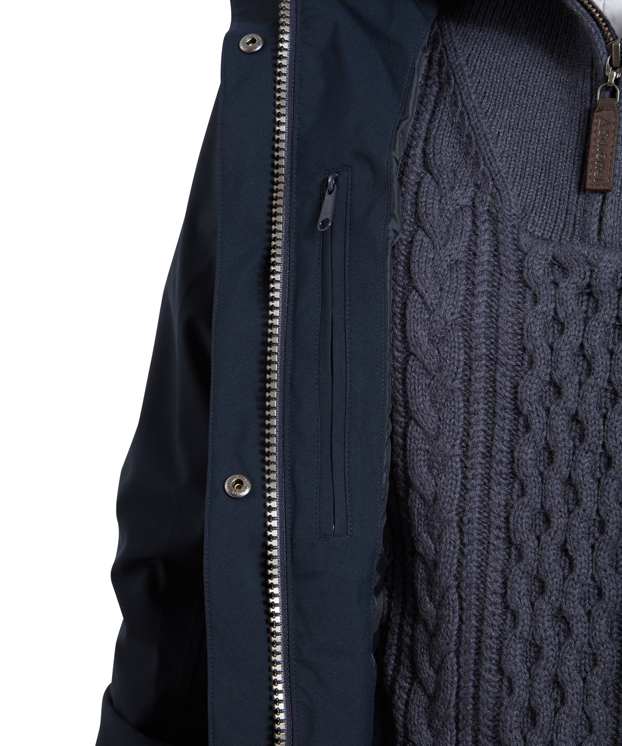 A close-up view of the Schöffel Teal Ultralight Coat for Women in Blue’s interior, showing the zippered inner pocket. The navy-blue lining and silver zipper are clearly visible, with the interior showcasing a cable-knit sweater underneath, adding texture and warmth to the look.