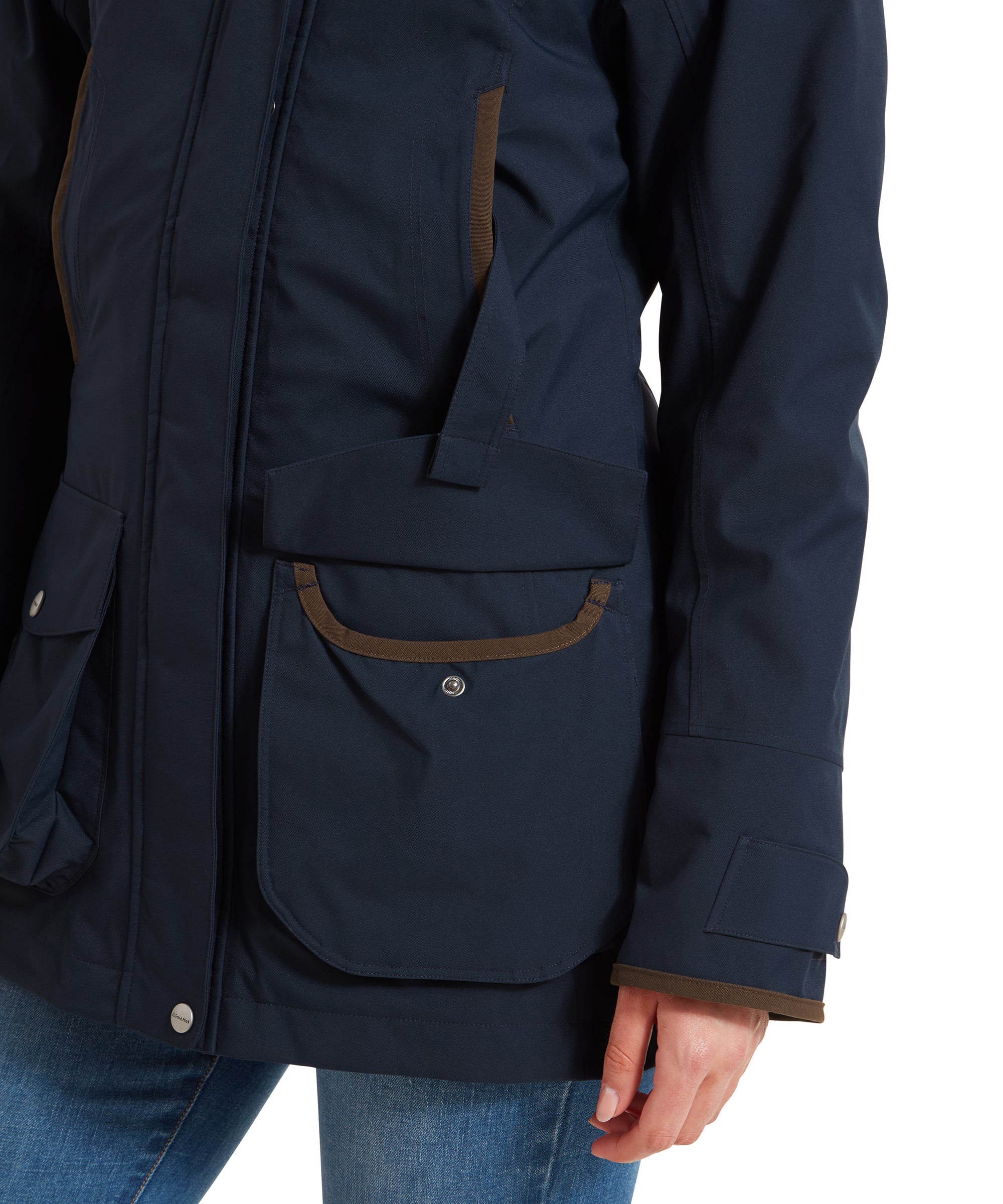 A detailed shot of the Schöffel Teal Ultralight Coat for Women in Blue’s sleeve cuff and the front pocket. The sleeve is secured with a snap button, which is engraved with the brand name “Schöffel.” The pocket flap is also visible, showcasing the same button detail and brown trim.