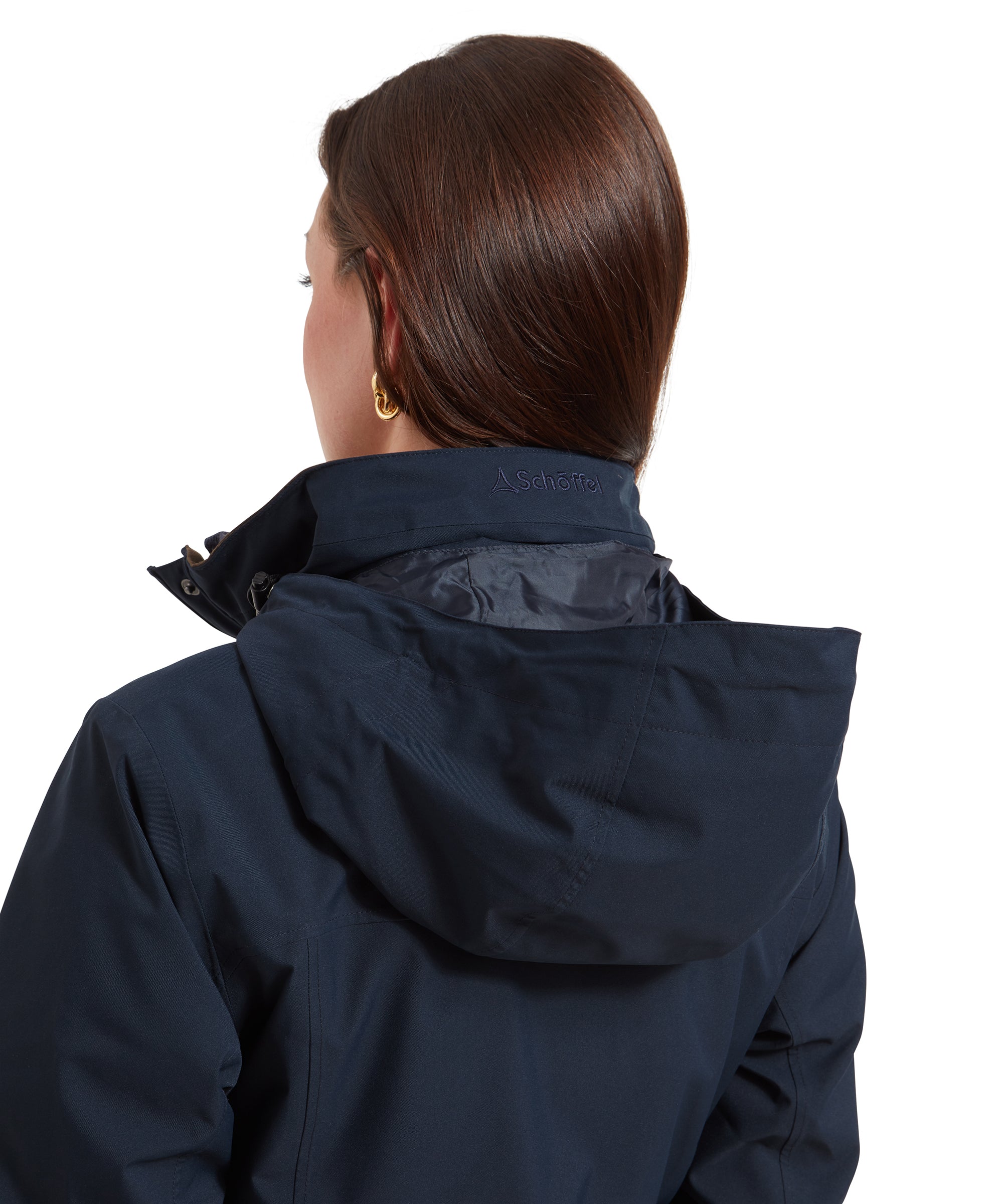 A close-up view of the back of the Schöffel Teal Ultralight Coat for Women in Blue’s collar, showing the attached hood. The brand name “Schöffel” is subtly embroidered on the collar, which is raised to cover the neck. The hood has a slightly glossy lining, adding a touch of contrast to the matte fabric of the jacket.