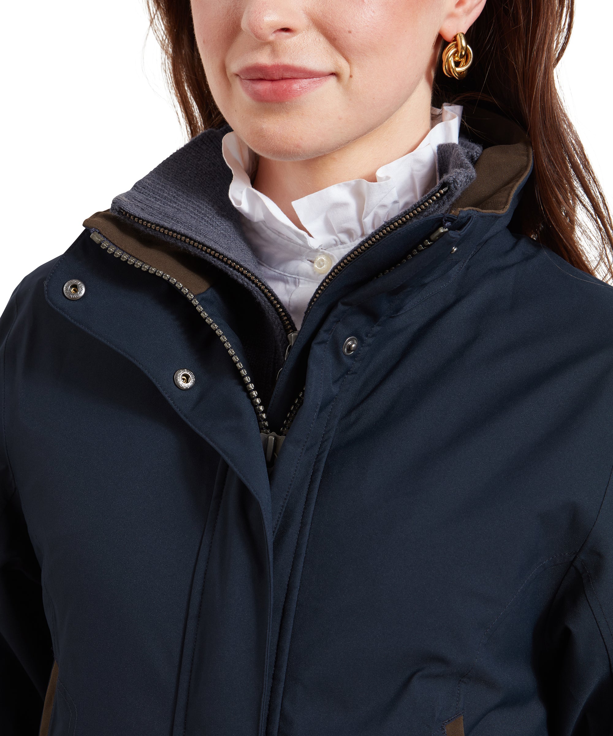 A close-up view of the Schöffel Teal Ultralight Coat for Women in Blue’s collar area, focusing on the high collar and zipper details. The collar is partially unzipped, revealing the layered shirt and sweater underneath. The brown trim along the collar adds a touch of contrast, complementing the gold earrings worn by the woman.