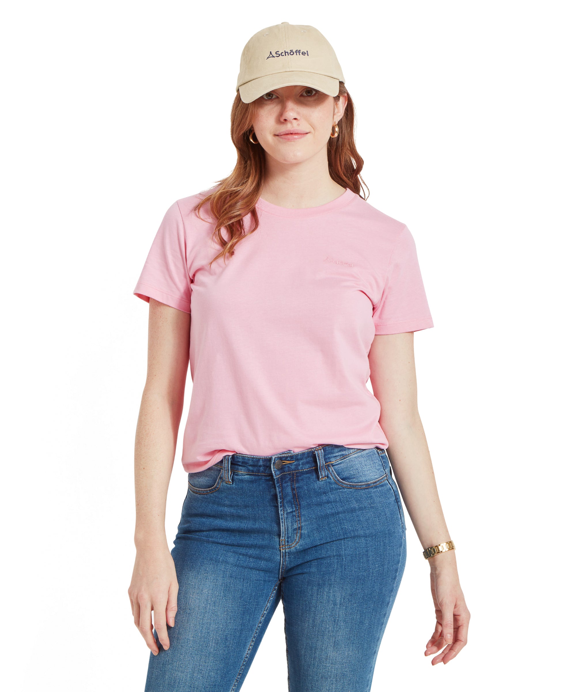 Model wearing Schöffel Women's Tresco T-Shirt in Pink with blue jeans and a beige cap, looking at the camera.