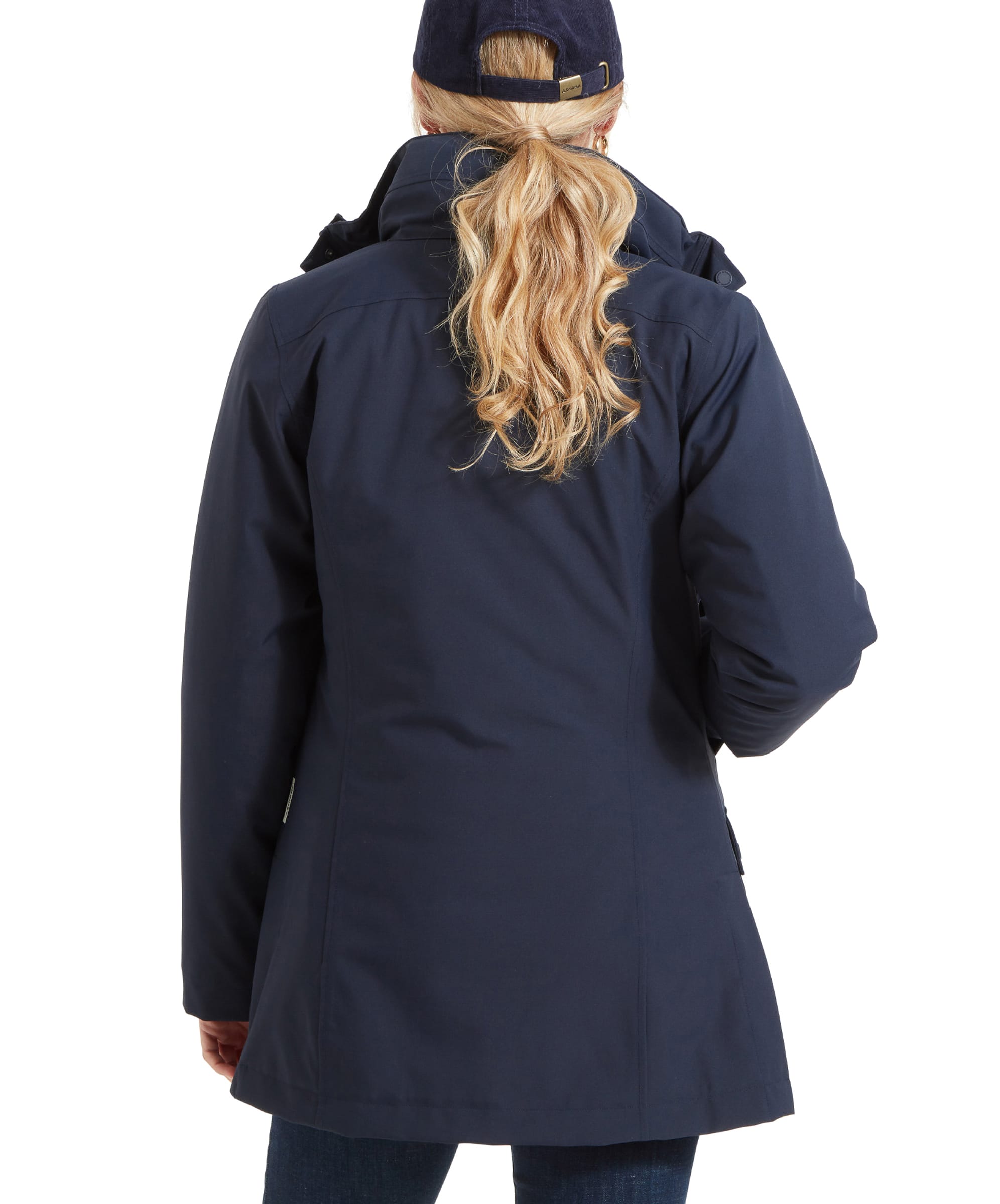 The back view of the same woman, highlighting the back design of the Schöffel Uppingham 3-in-1 Coat for Women in Blue. The coat covers her hips, and her blonde hair is pulled through the back of her baseball cap in a low ponytail. The fit of the coat is slightly tapered, giving it a tailored appearance.