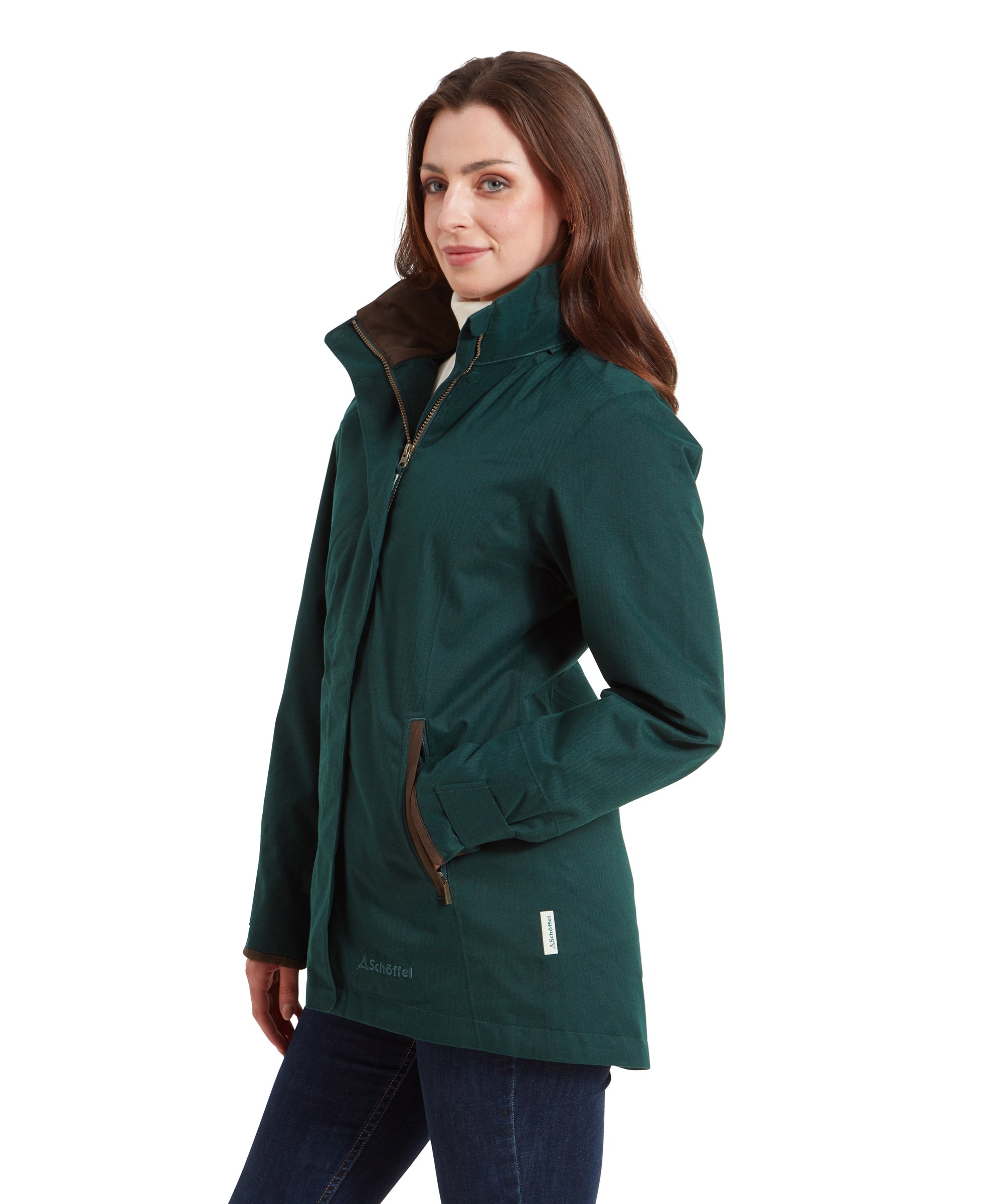 A side view of a woman modelling the Schöffel Wakerley Jacket for Women in Green with her hand in the pocket whilst looking away. You can see the clean and siomple design of the jacket and the dipped hem at the back of the jacket compared to the front.