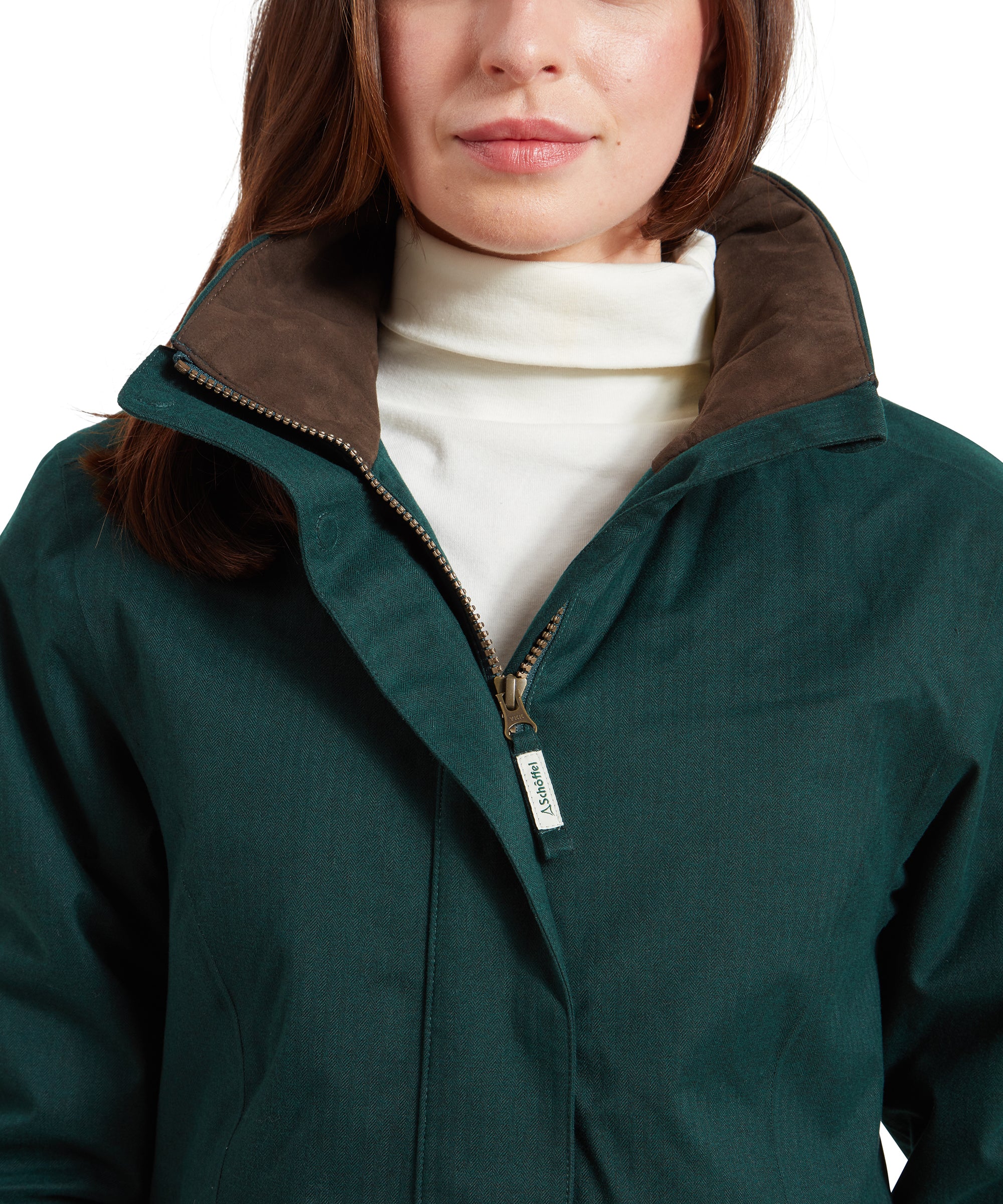 A close-up of the collar and zipper area on the Schöffel Wakerley Jacket for Women in Green. The woman wears the jacket zipped up slightly and the collar opened side to highlight the brown suedette finish to the inside. A Schöffel branded fabric zipper pull can be seen.