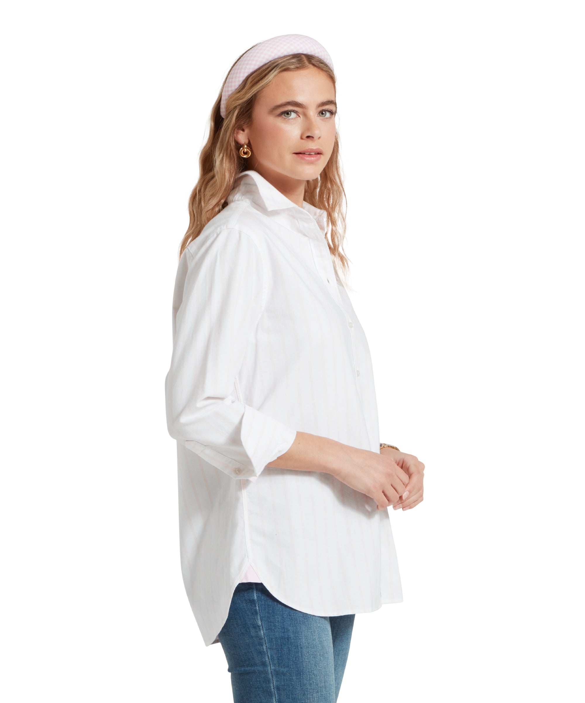 Side profile image of a female model wearing a white and pink striped Schöffel shirt, paired with a pair of mid wash denim jeans.