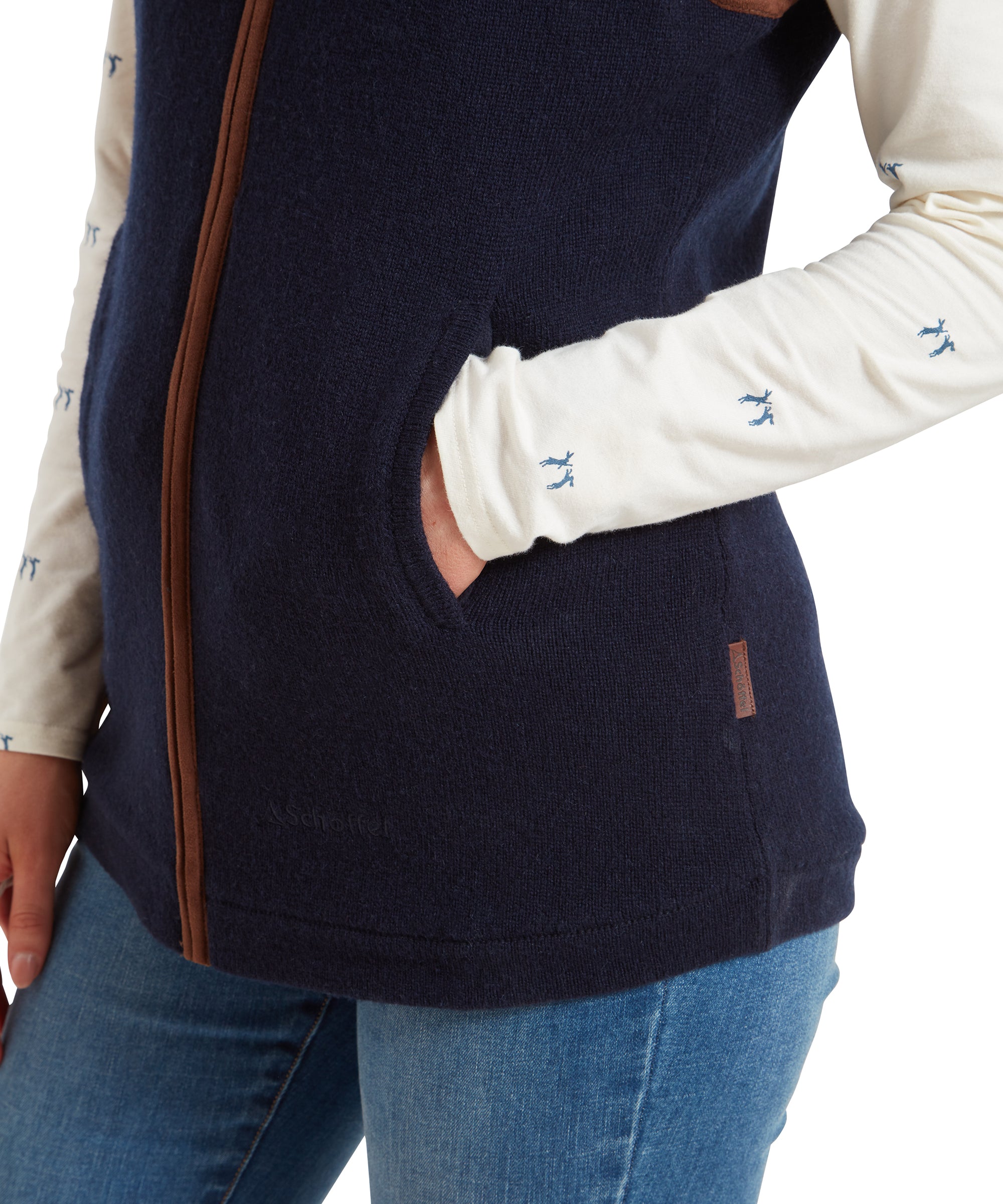 A close-up of the lower half of the Schöffel Women's Lambswool Aerobloc Gilet for Womens in Navy, highlighting the brown trim, zipper detail, and the woman's hand in the pocket.