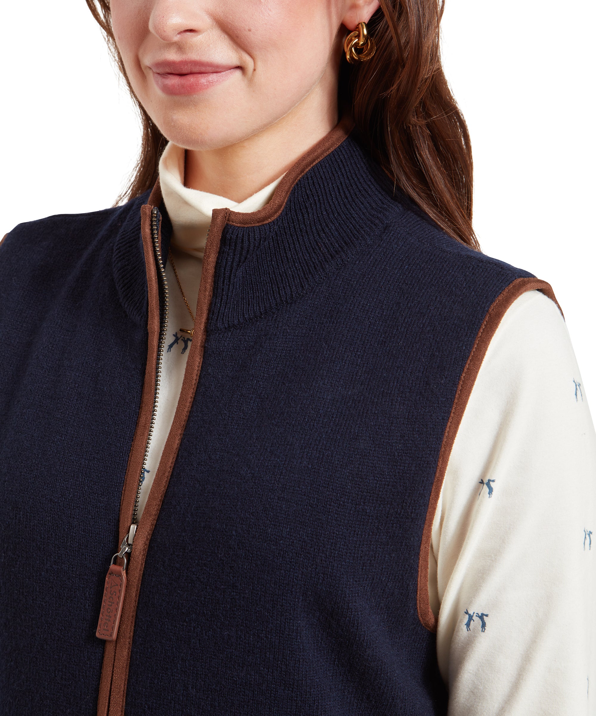 A close-up shot of the upper part of the Schöffel Women's Lambswool Aerobloc Gilet for Womens in Navy, showing the brown trim around the collar and the zipper, with the cream top underneath.